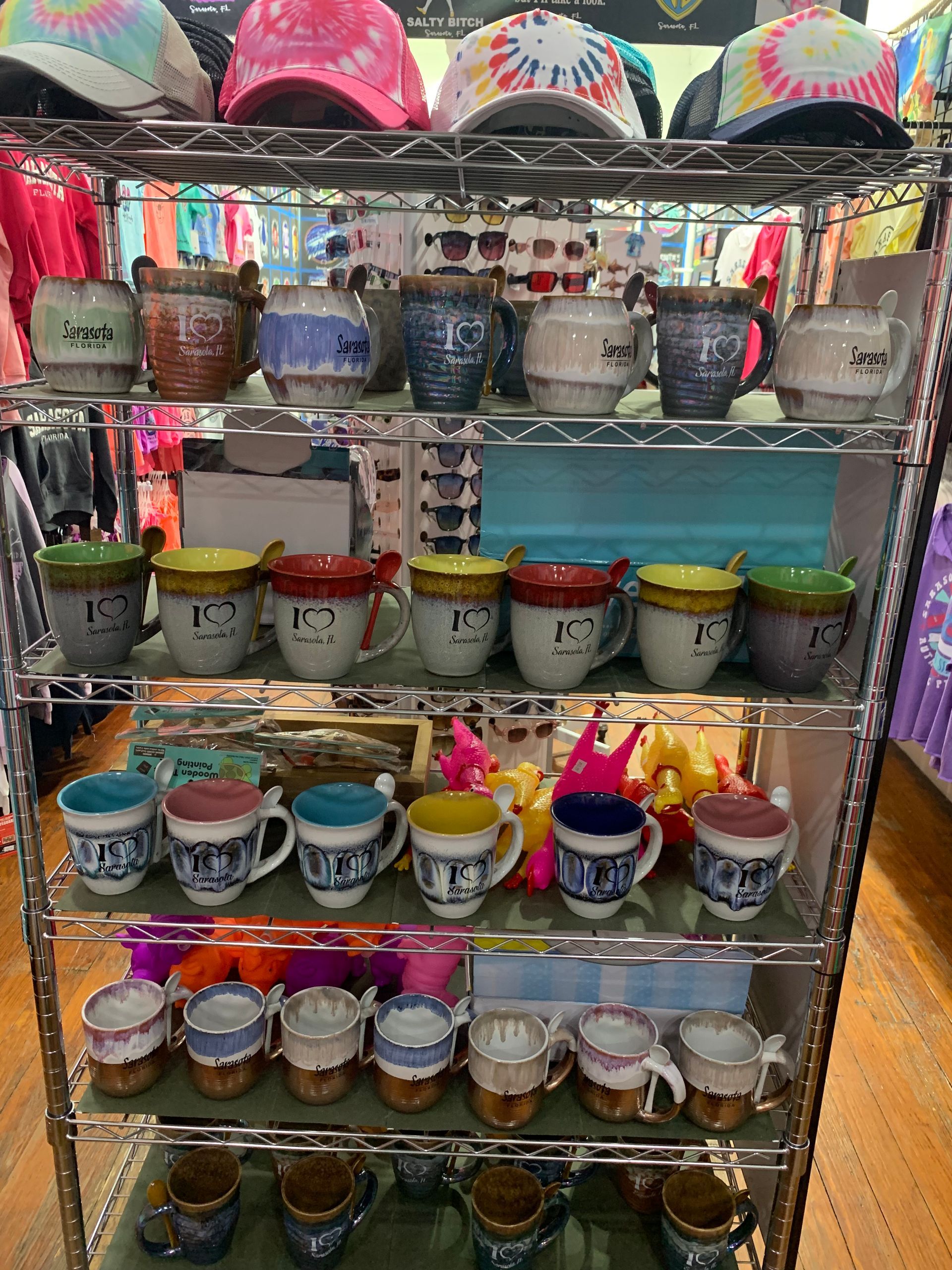 Display rack of colorful mugs and tie-dye hats.