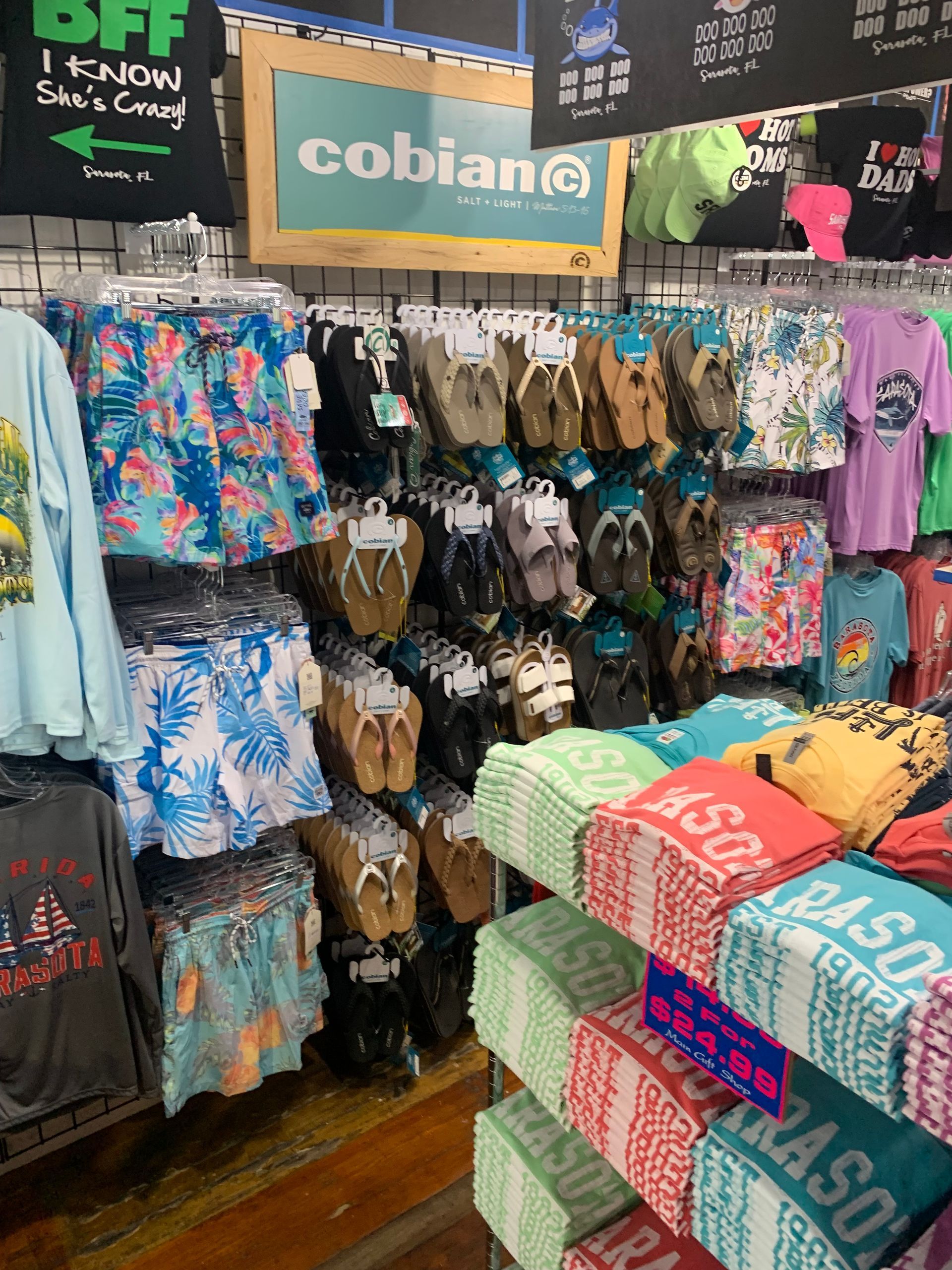 Store display of flip-flops and beachwear, including shorts, t-shirts, and towels, with a 