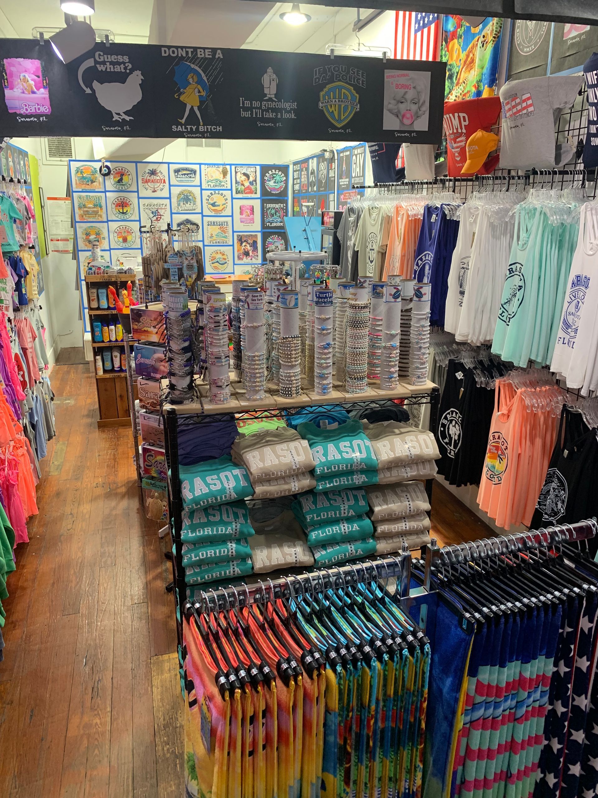Inside a souvenir shop: clothing racks, stacked shirts, and merchandise displays.