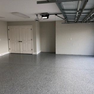 An empty garage with a garage door opener and a gray floor.