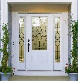 White front door with glass panels and decorative ironwork, flanked by sidelights. Potted plants on each side.