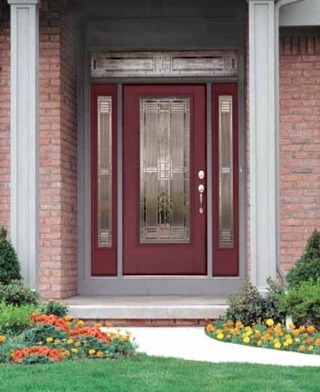 Red front door with glass panels and sidelights on a brick house.