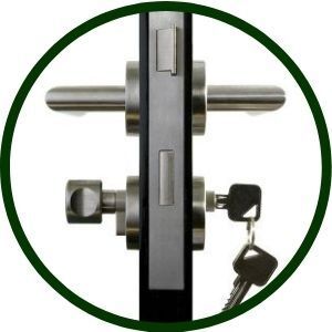 Close-up of a door lock with a handle on the left and a key in the lower lock. Silver hardware on a black door.