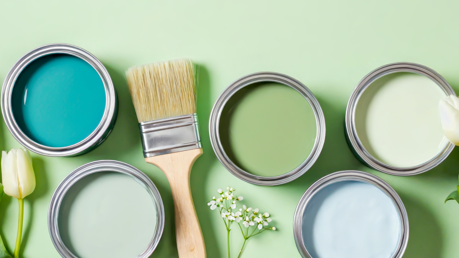 A bunch of cans of paint , a brush , and flowers on a green background.