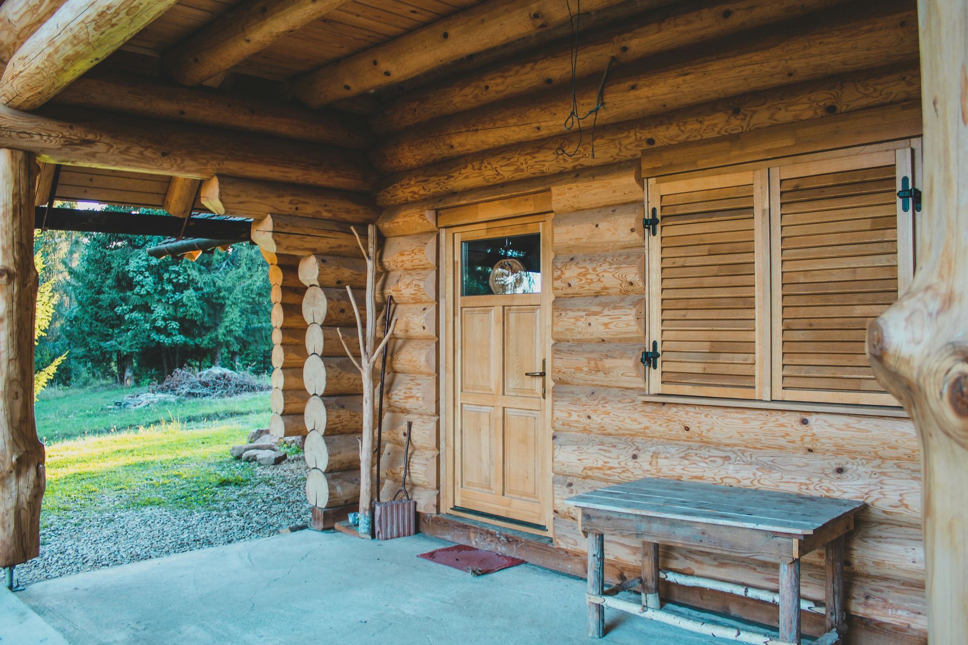 A log cabin with a porch and a table in front of it.