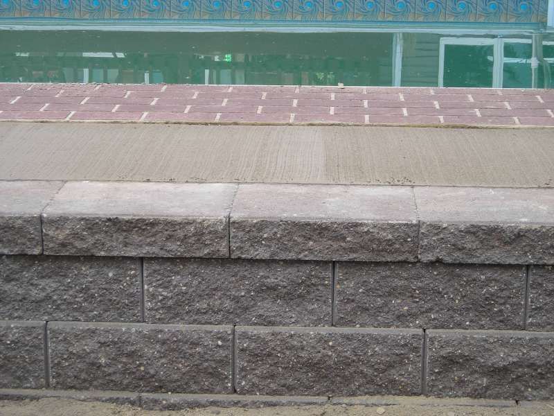A brick wall is next to a swimming pool.