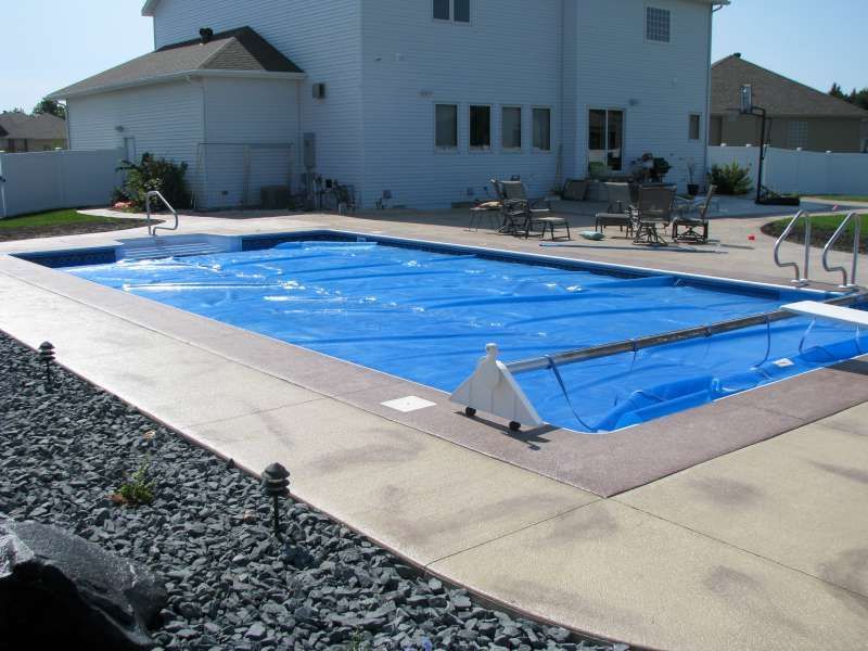 A large swimming pool with a blue cover on it