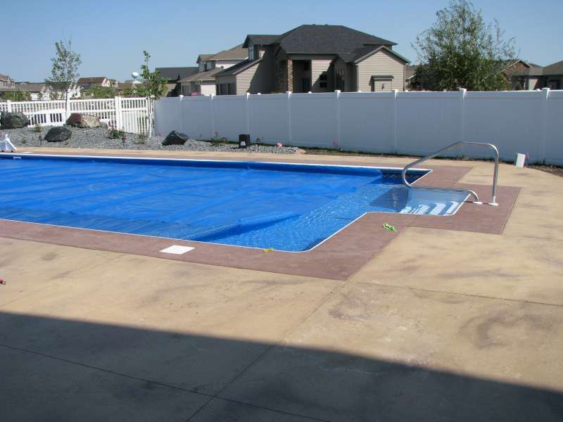A large blue swimming pool with a white fence surrounding it