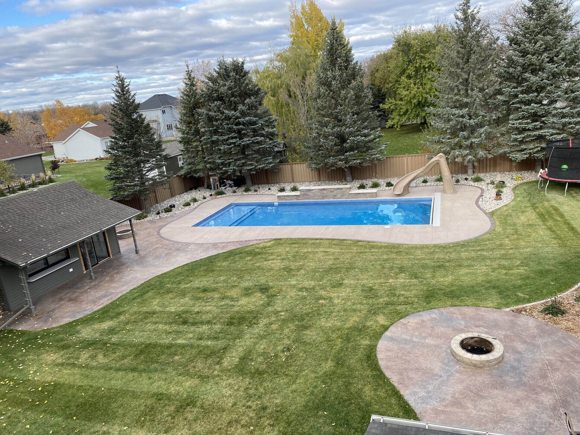 An aerial view of a backyard with a large swimming pool and a fire pit.