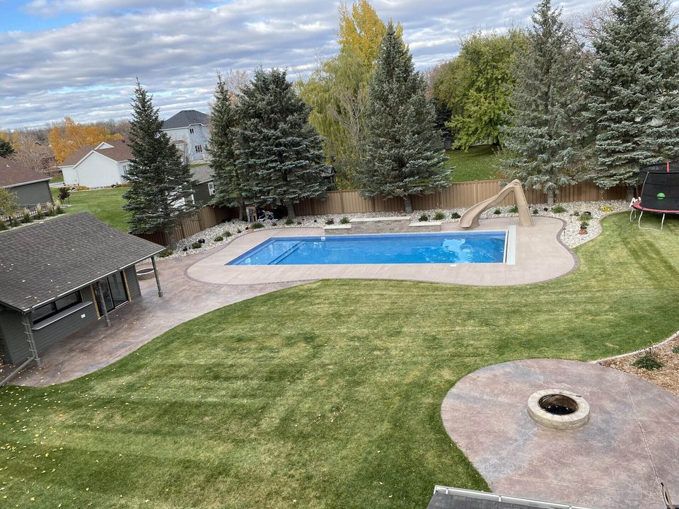 An aerial view of a backyard with a large swimming pool and a fire pit.