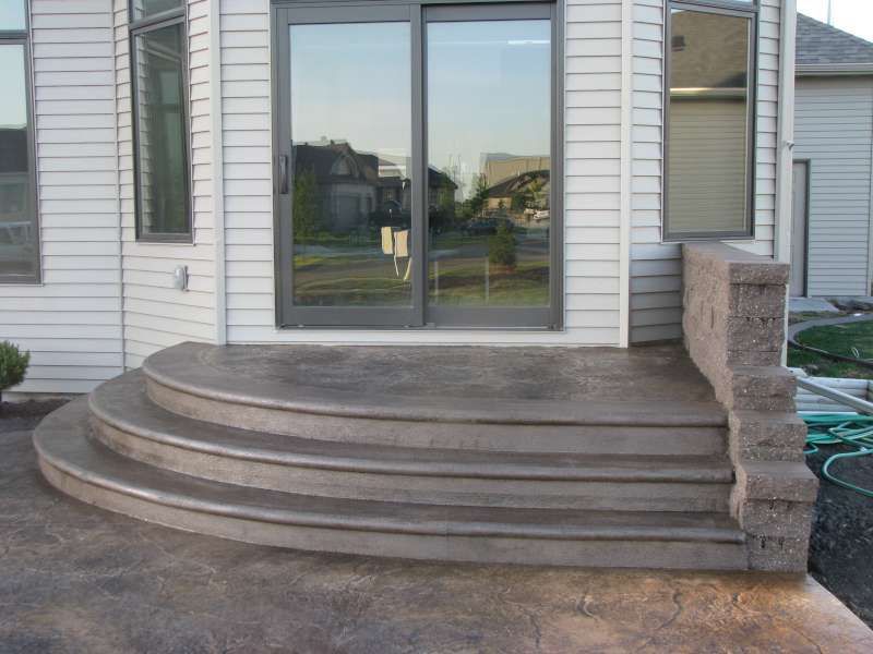 A concrete patio with stairs and a fire pit.