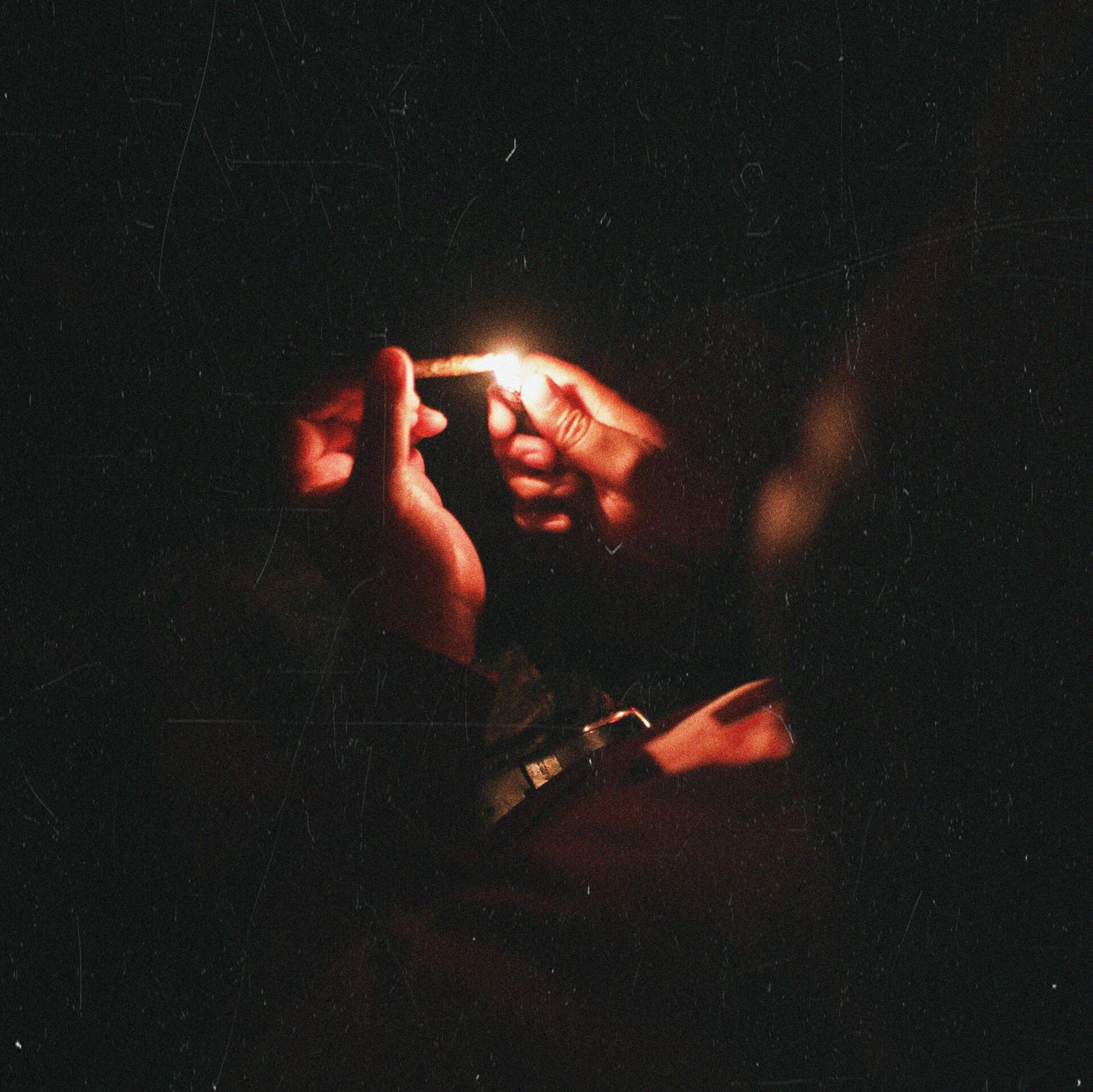 Hands lighting a joint in the dark