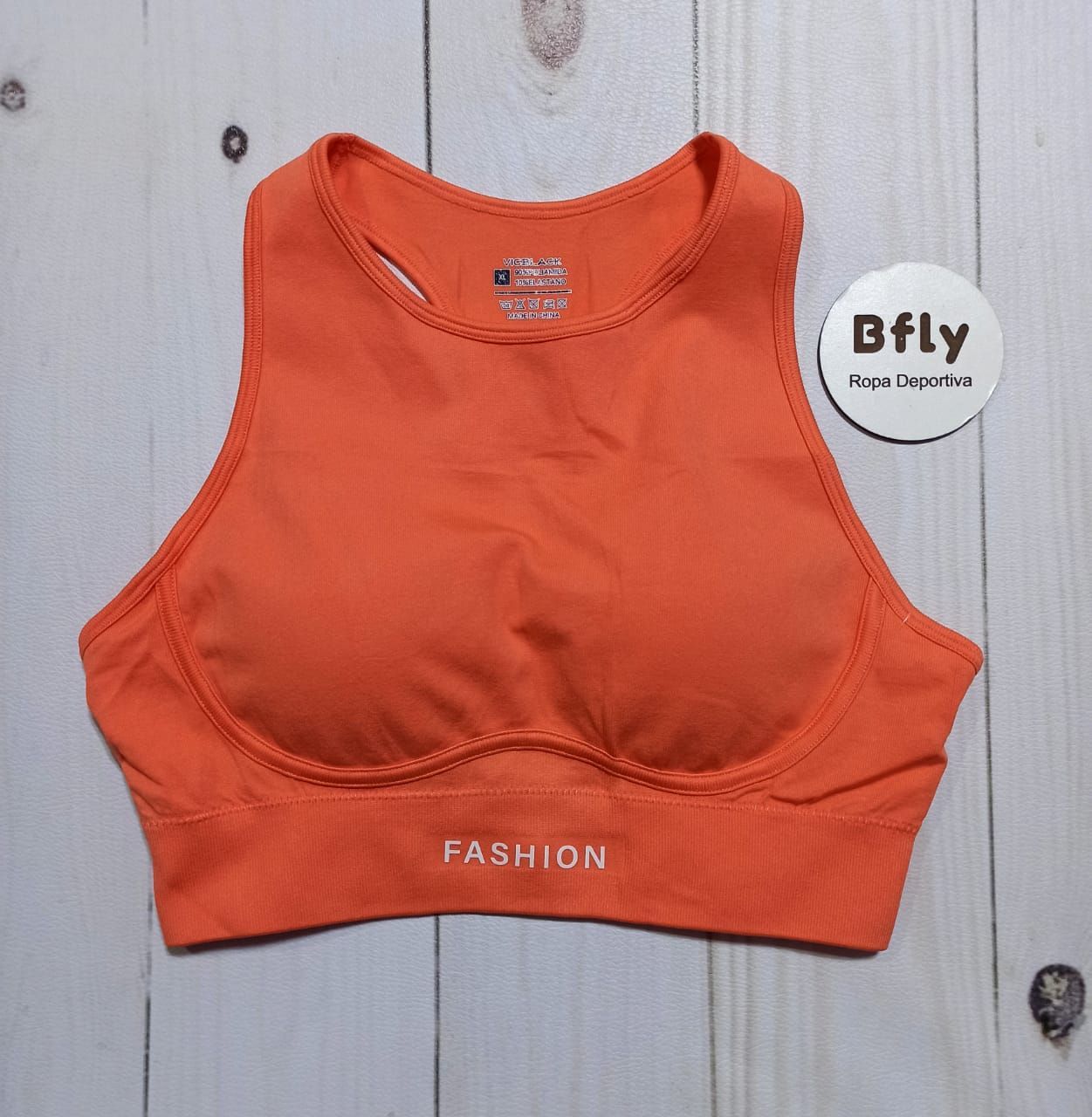 Sujetador deportivo naranja con "FASHION" impreso en la parte inferior.