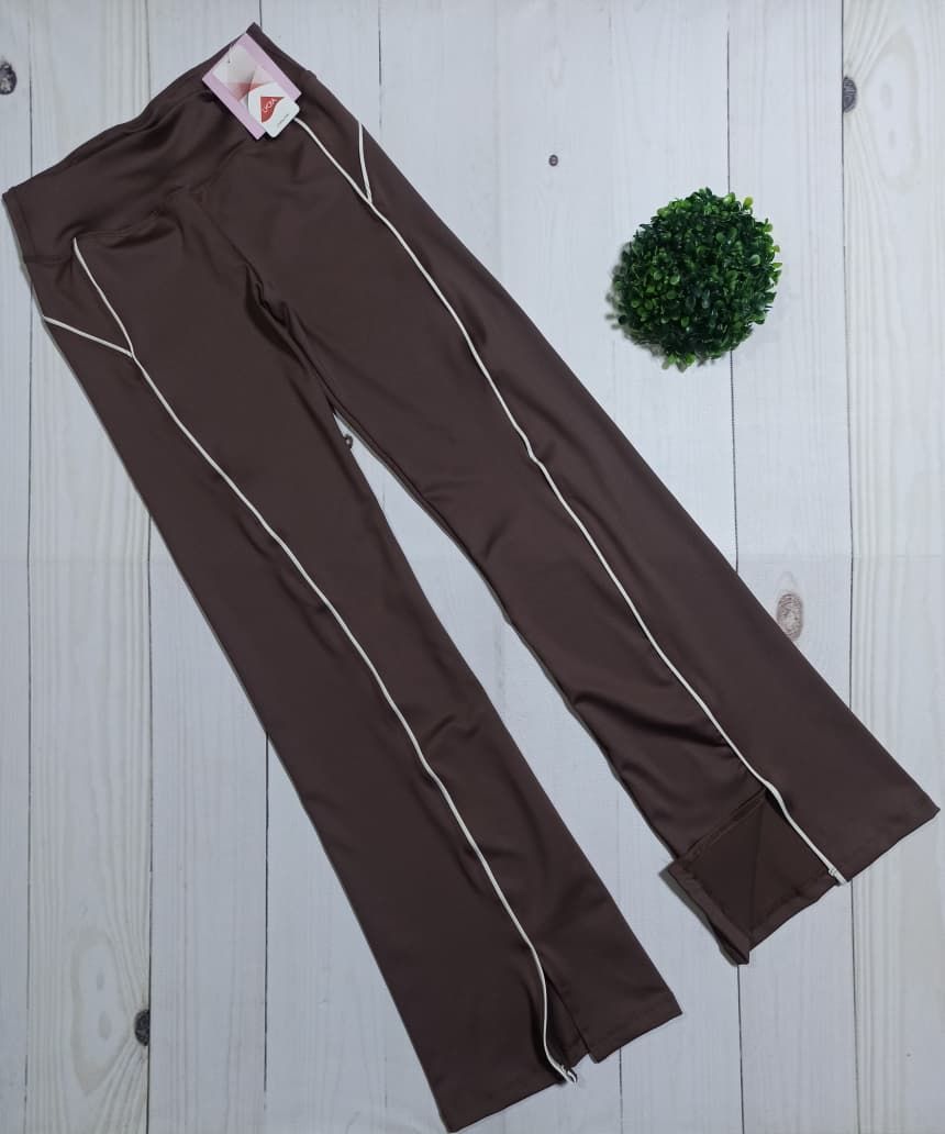 Dos pantalones deportivos, de color marrón y negro, con ribetes blancos, sobre una superficie de madera.