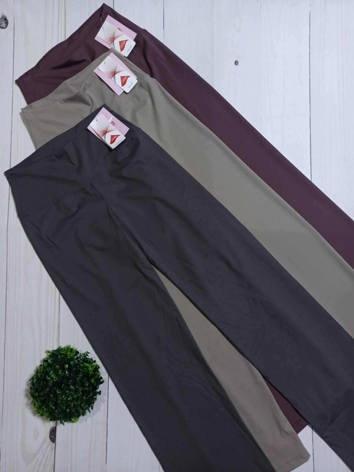 Tres pares de leggings en diferentes tonos de marrón sobre una superficie blanca, con etiquetas de precio.