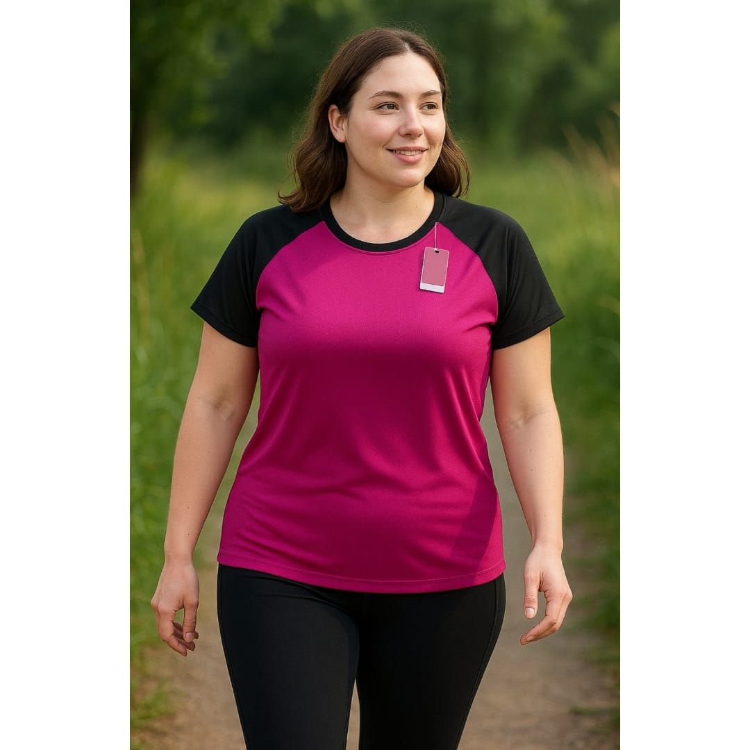 Mujer con camiseta deportiva color magenta y negra y leggings negros caminando por el sendero.