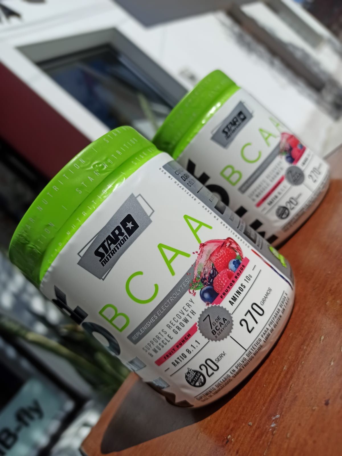 Dos botes blancos de suplemento BCAA de Star Nutrition con tapas verdes, en un entorno soleado.