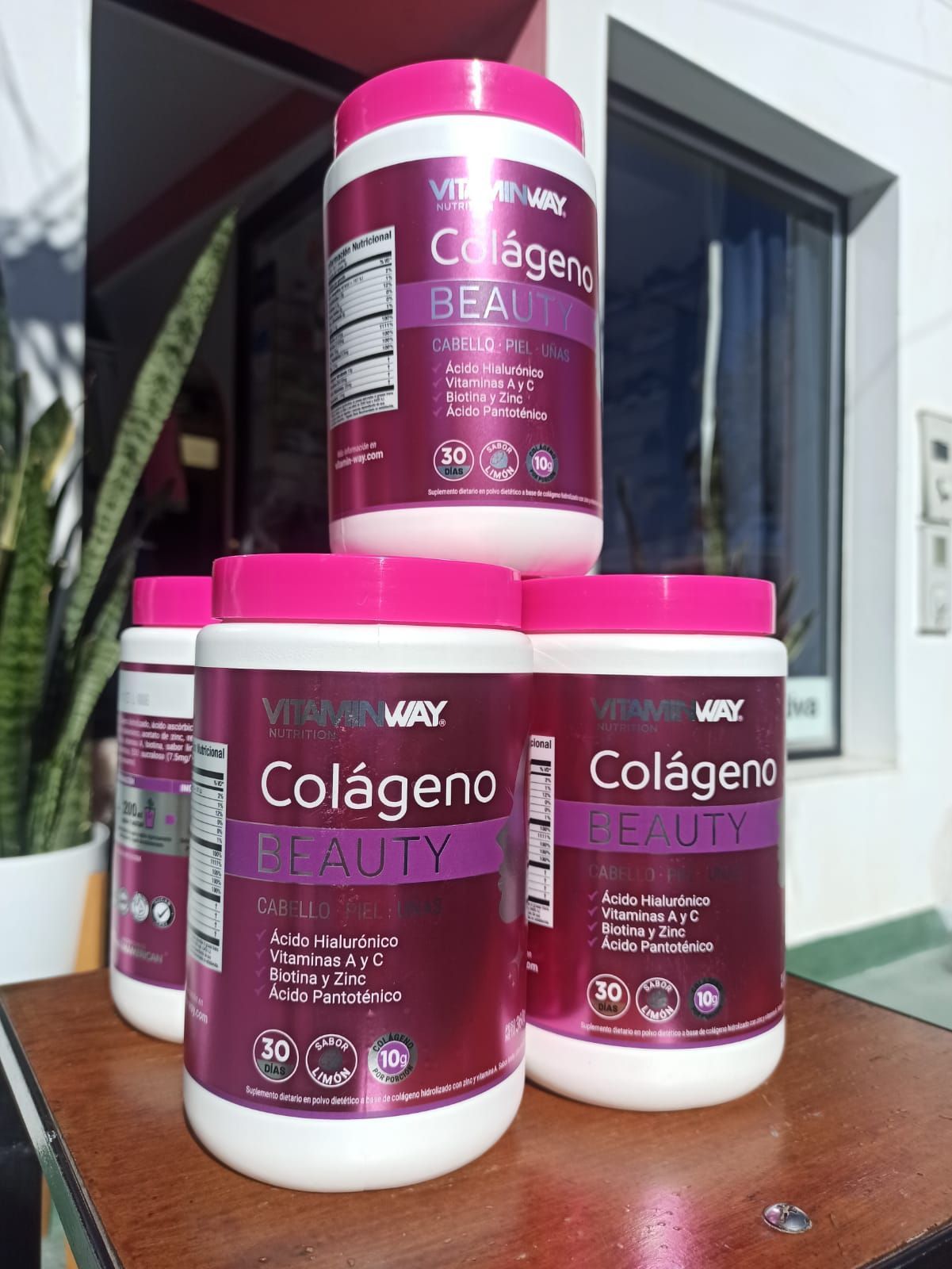 Envases de color rosa y blanco del suplemento de colágeno “Colágeno Beauty”, apilados sobre una mesa.