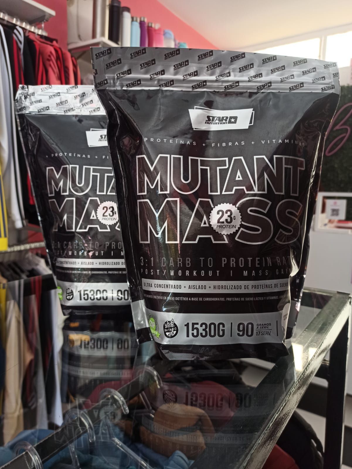Dos bolsas de proteína en polvo Mutant Mass en un estante de una tienda. Bolsas negras con texto blanco.