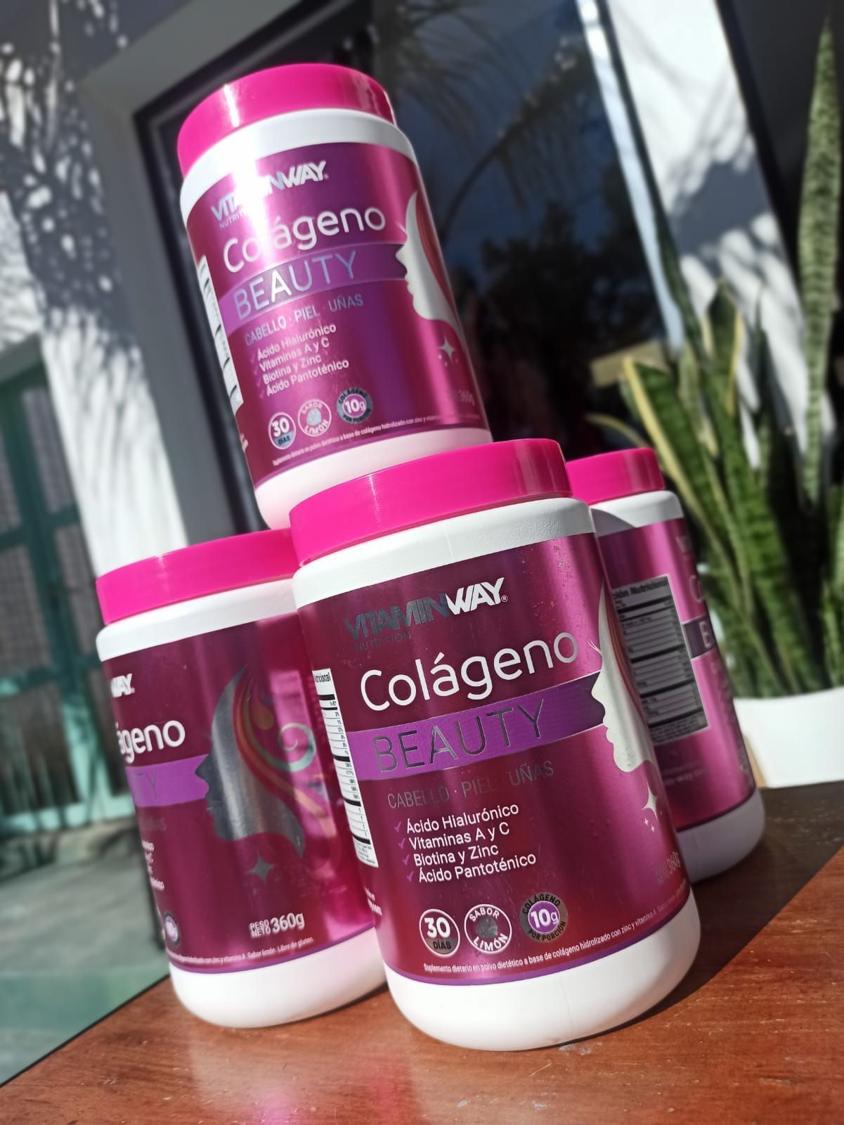 Envases de color rosa y blanco del suplemento de colágeno “Colágeno Beauty”, apilados sobre una mesa.