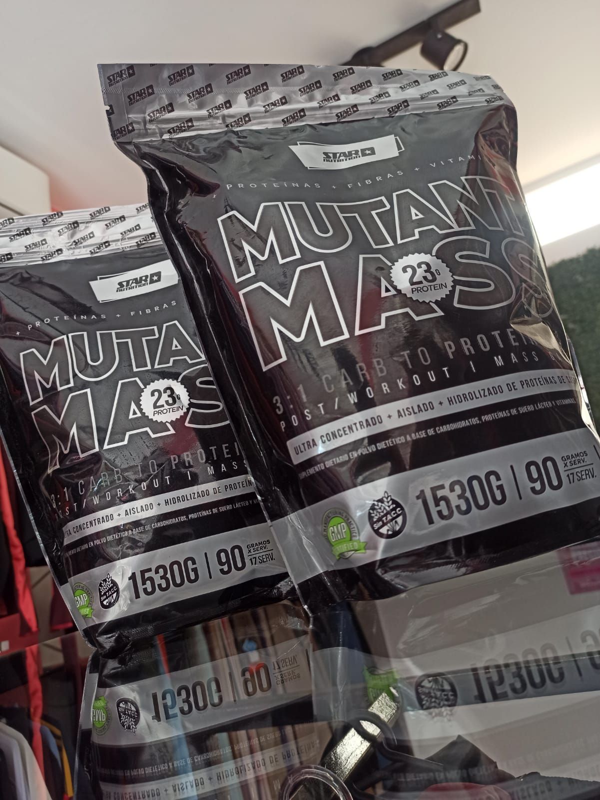 Dos bolsas de proteína en polvo Mutant Mass en un estante de una tienda. Bolsas negras con texto blanco.