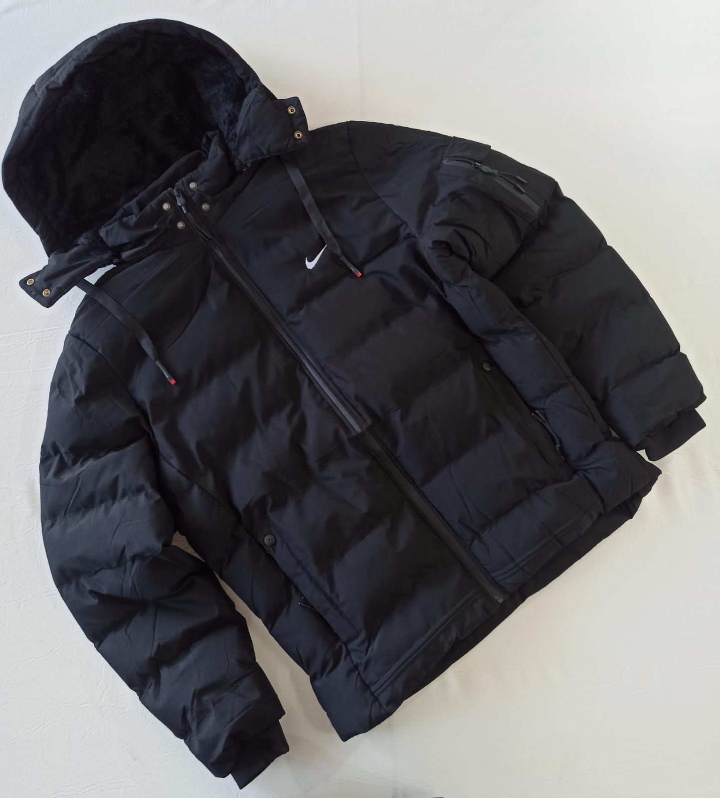 Chaqueta acolchada roja con capucha extendida sobre un fondo blanco.