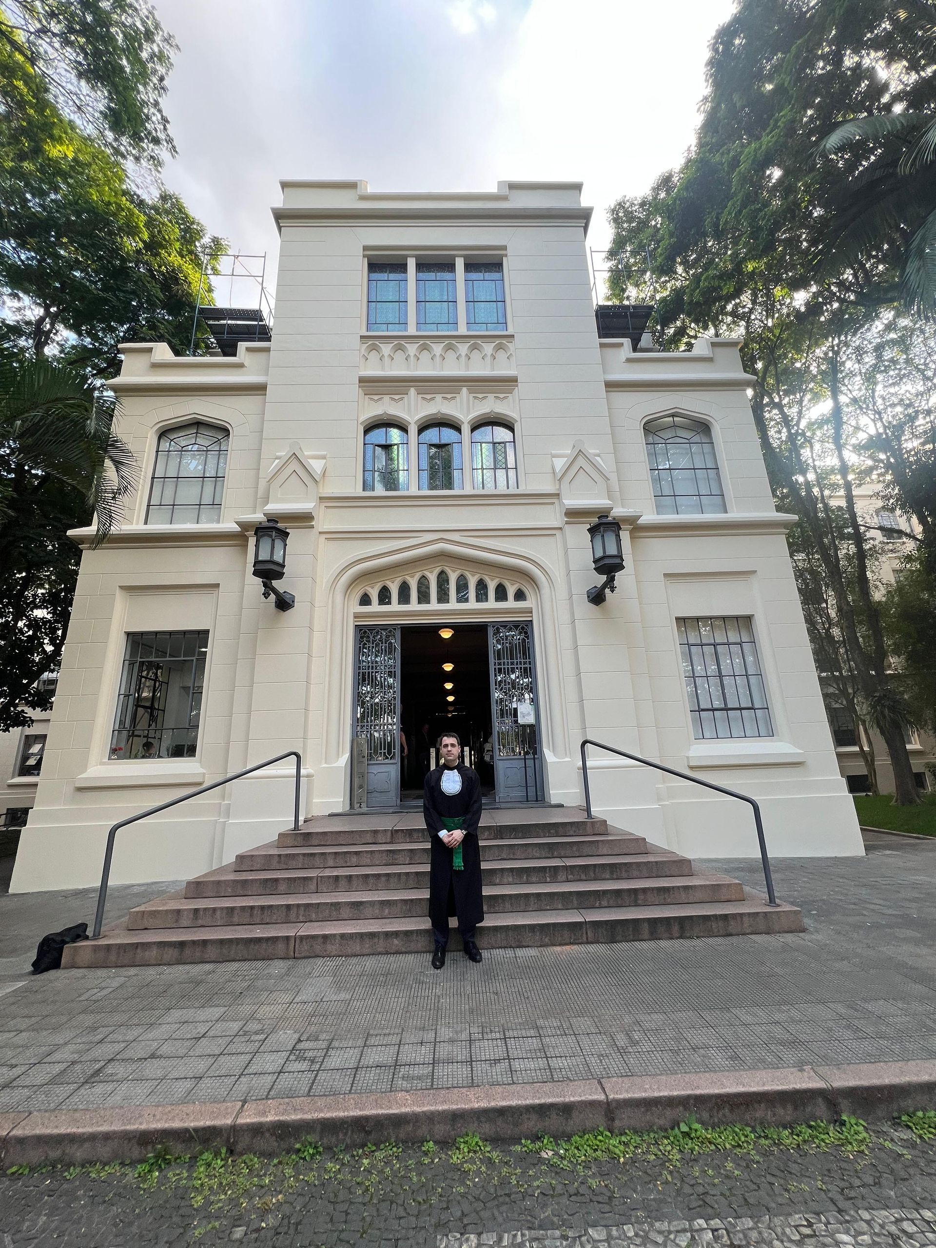 Um homem de smoking está parado em frente a um grande edifício branco.