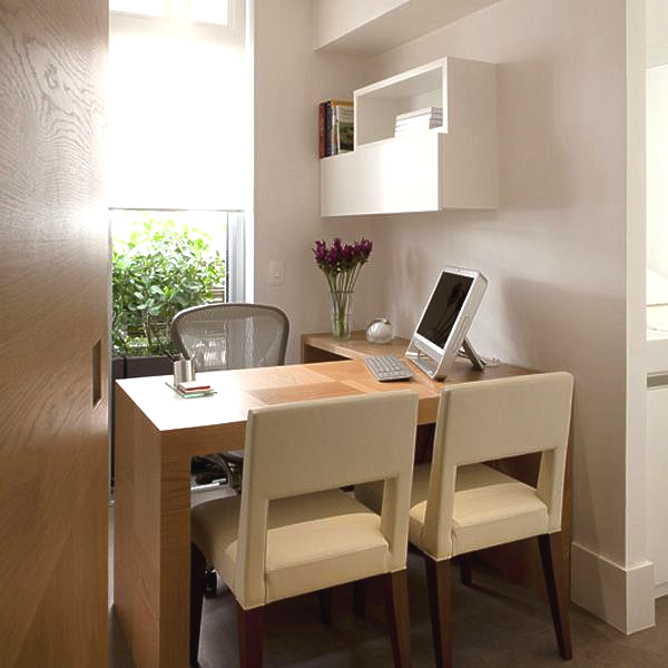 Uma mesa de madeira com um computador em cima dela em uma sala com cadeiras.