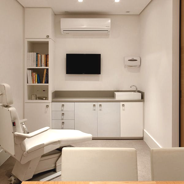 Uma mesa de madeira com um computador em cima dela em uma sala com cadeiras.