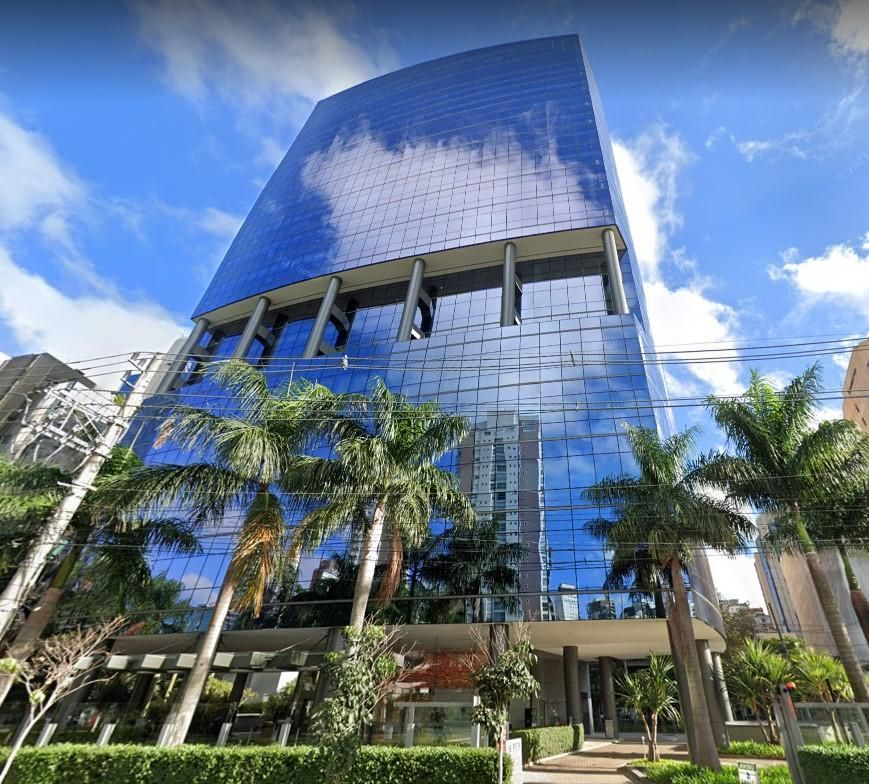 Uma mesa de madeira com um computador em cima dela em uma sala com cadeiras.