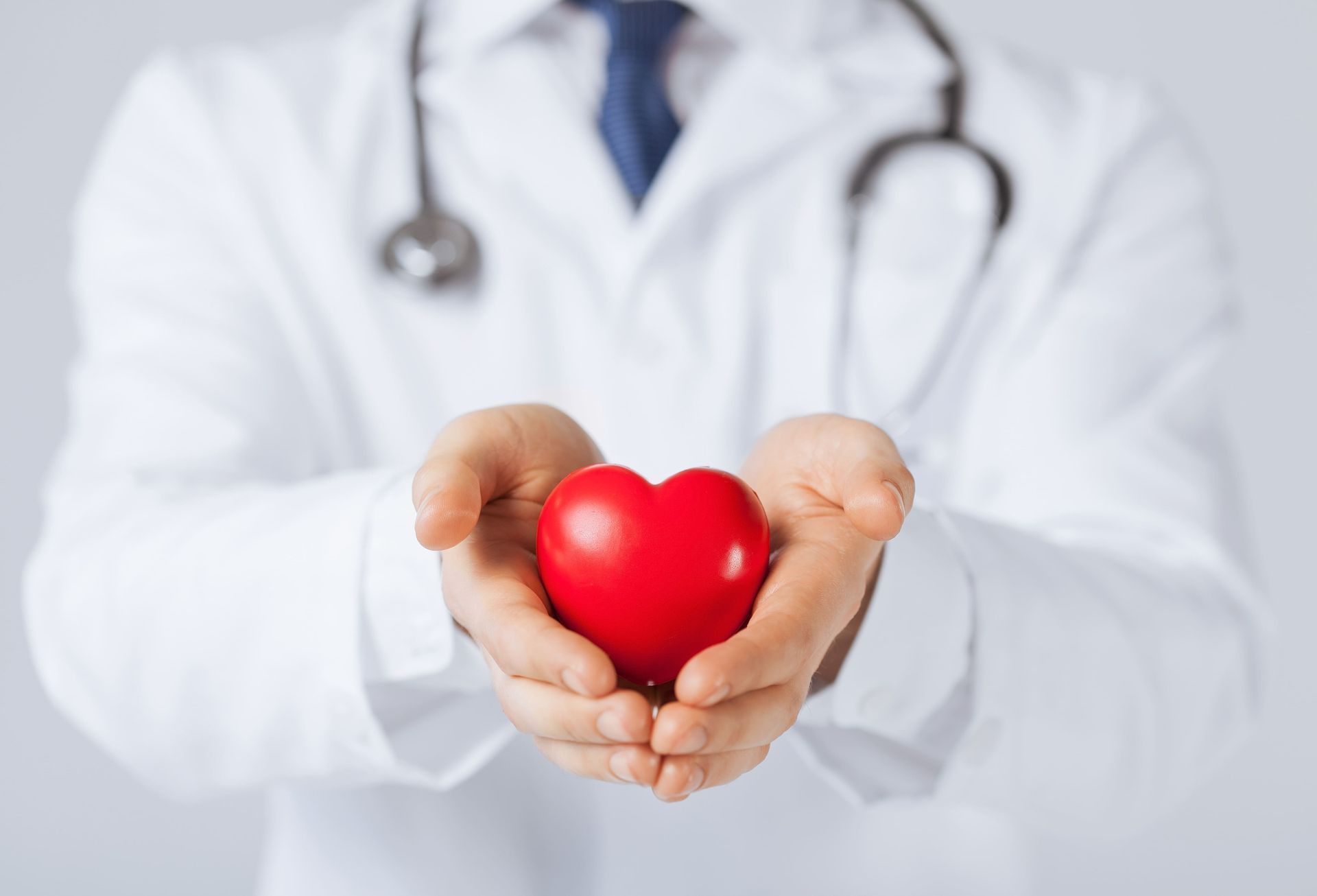 Um médico está segurando um coração vermelho em suas mãos.