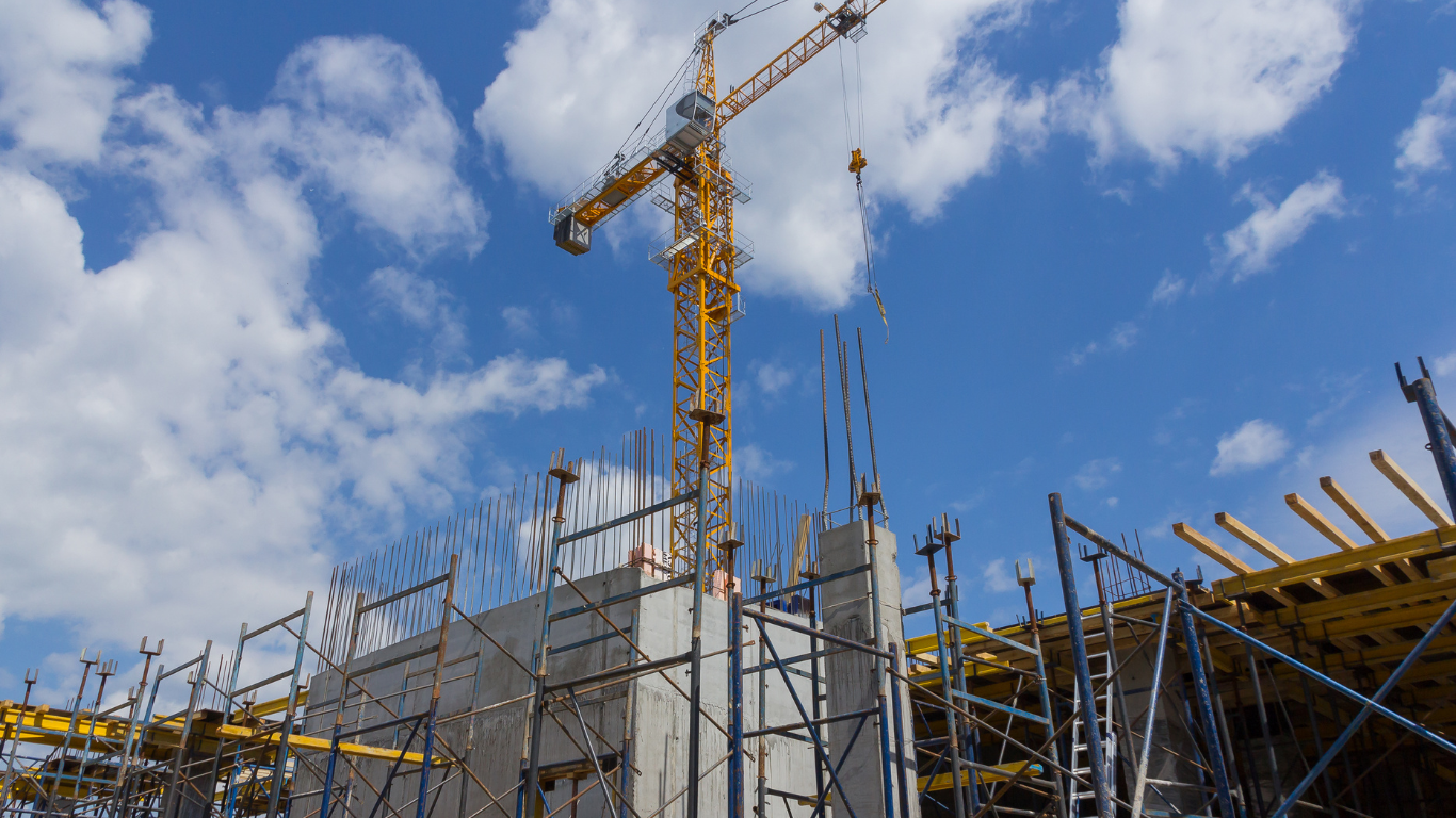 A construction site with a crane and scaffolding against a blue sky.