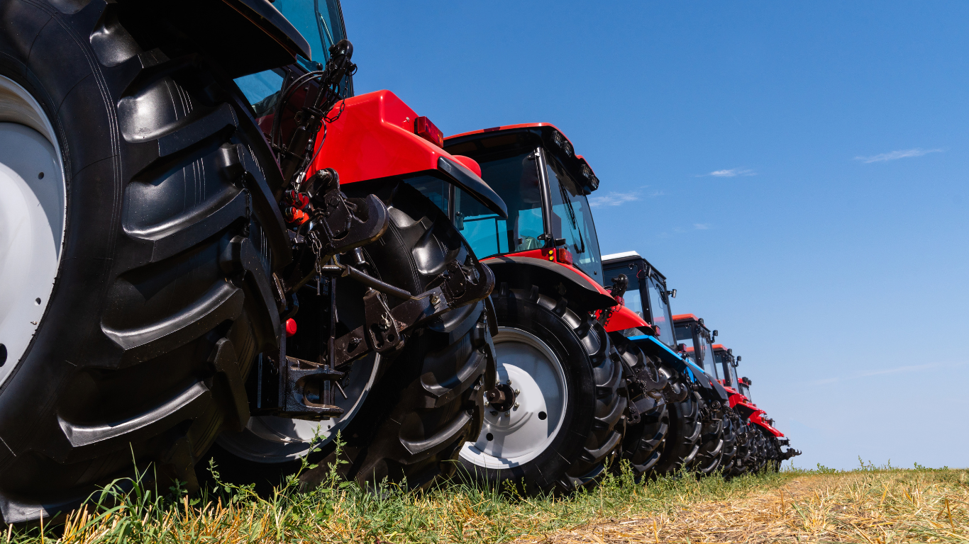 A row of tractors are parked in a field.