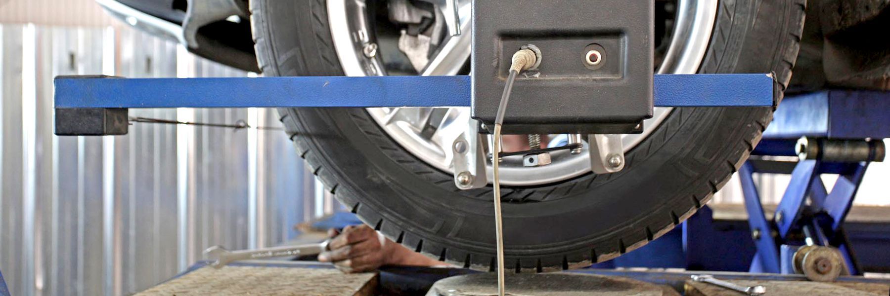 Cars raised on lifts in a repair shop; mechanic working on a vehicle.