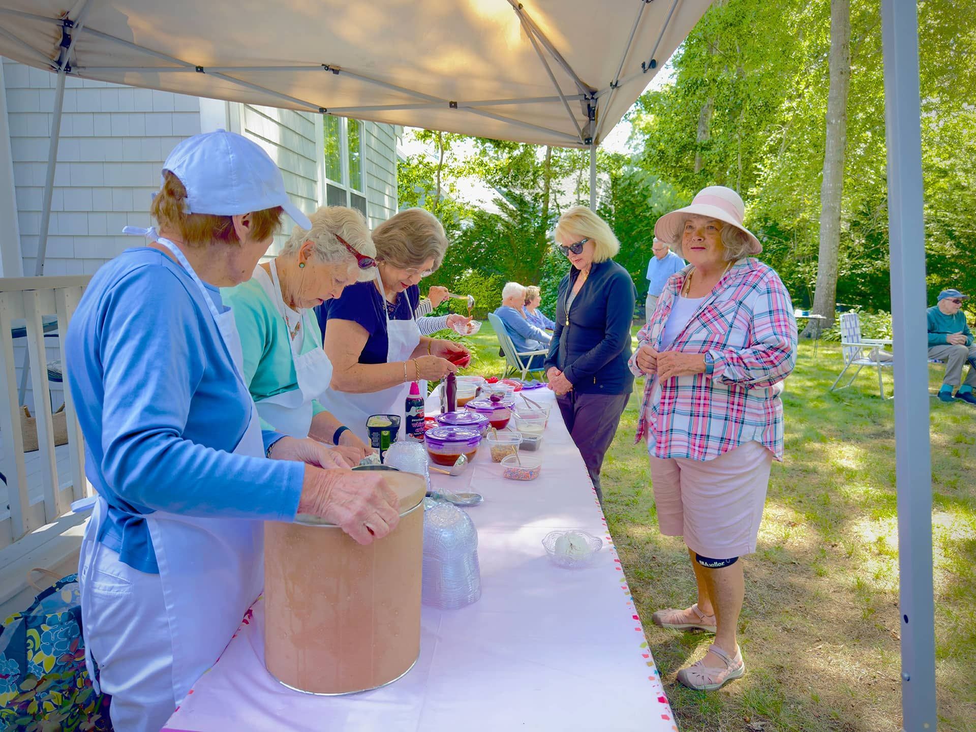 A group of women are standing around a table at an ice cream social