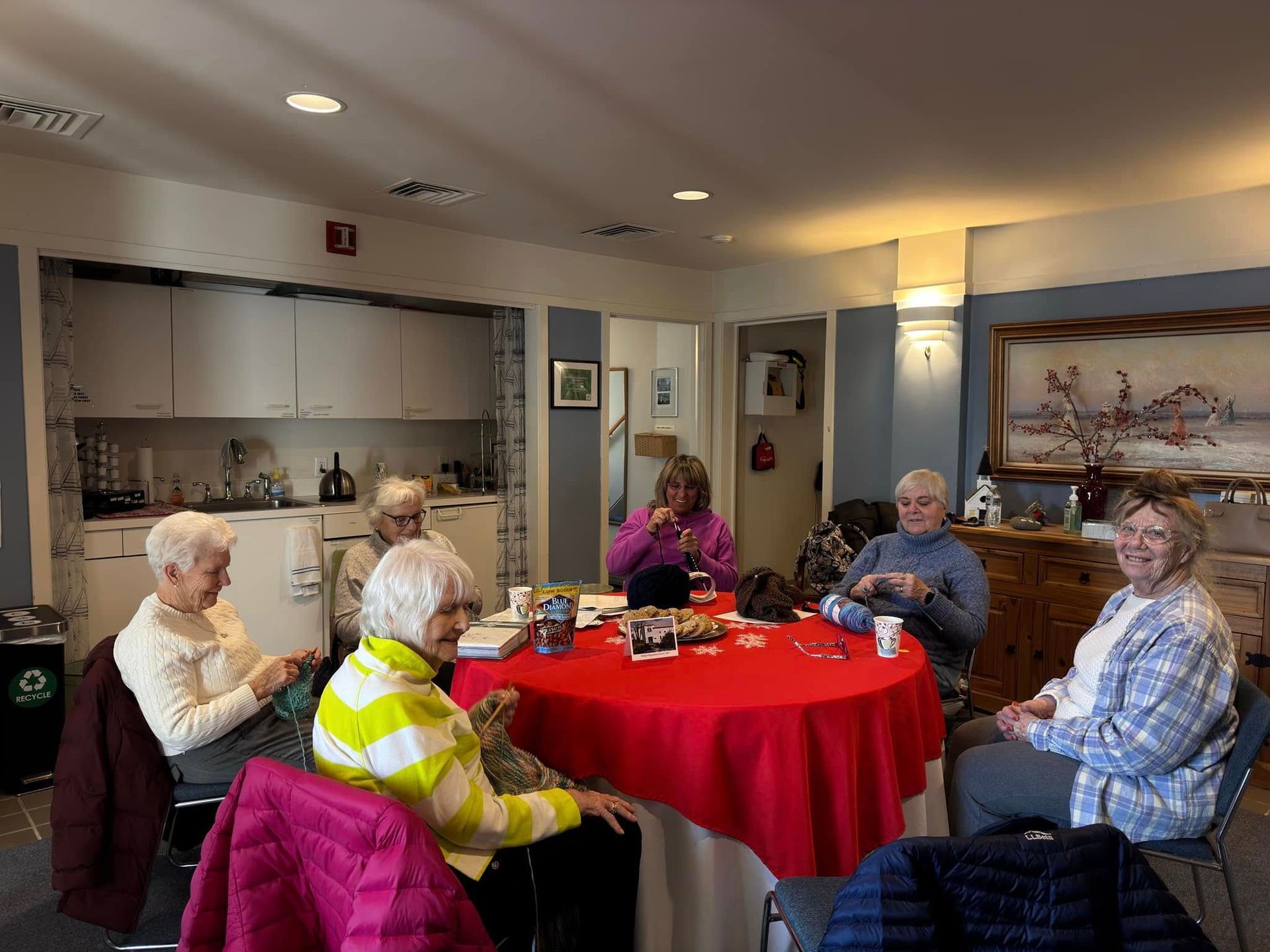 Three women holding a blanket in front of a building that says ' congratulations ' on it