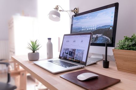 A laptop computer and a monitor are sitting on a wooden desk.