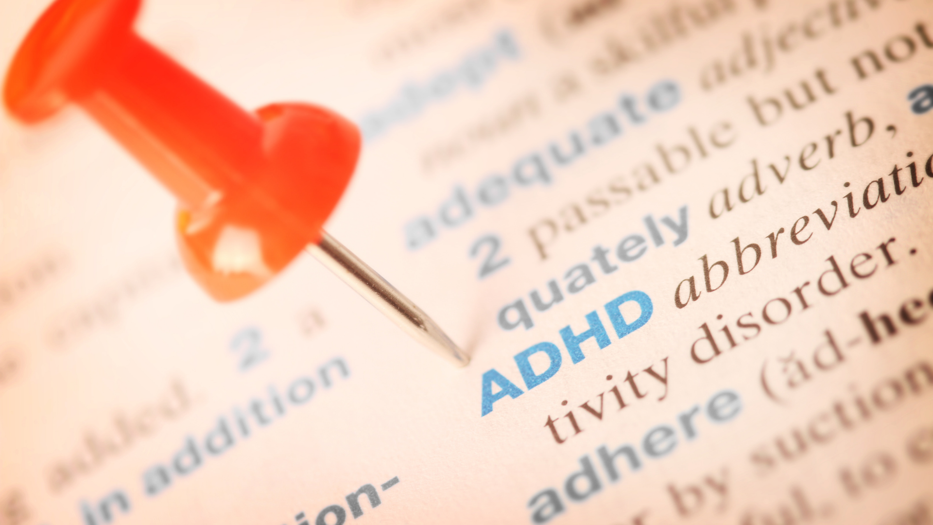 The word adhd is pinned to a page of a book