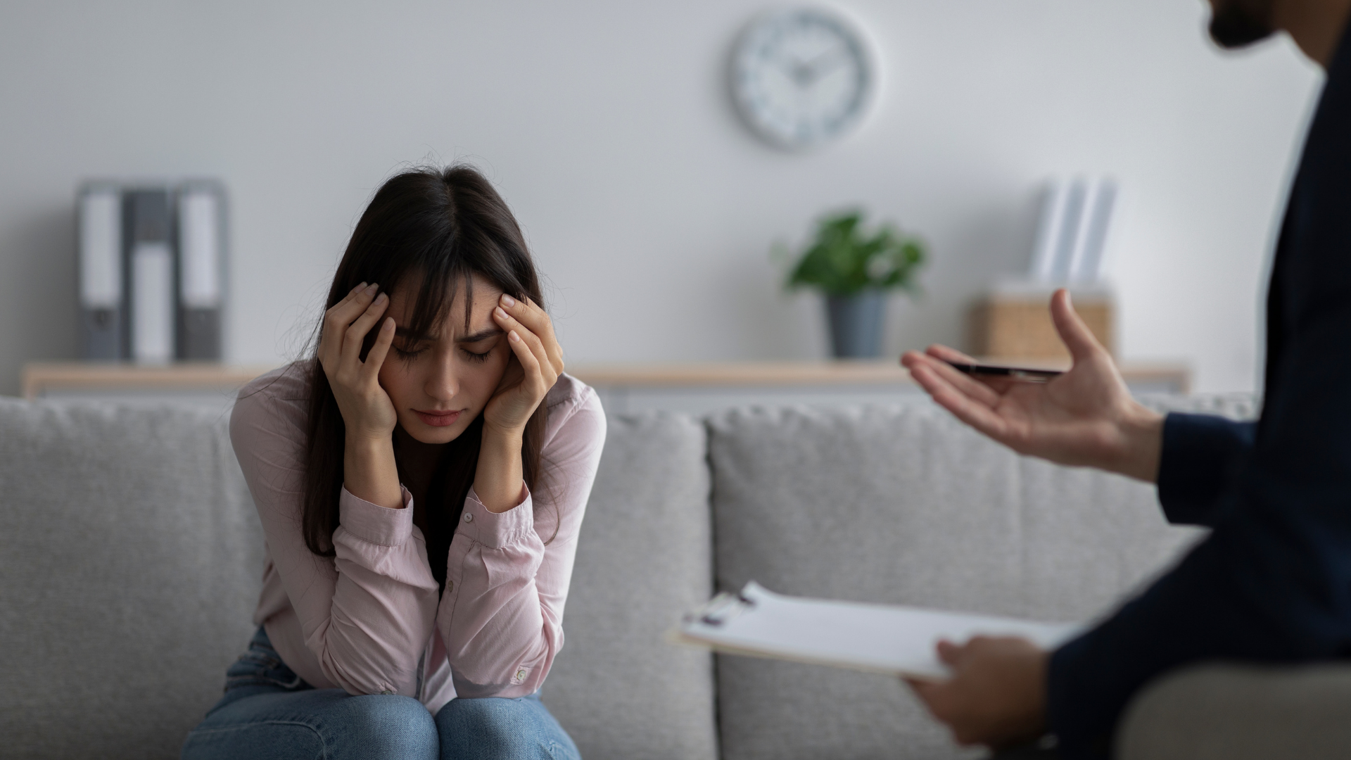 A woman is sitting on a couch talking to a man.
