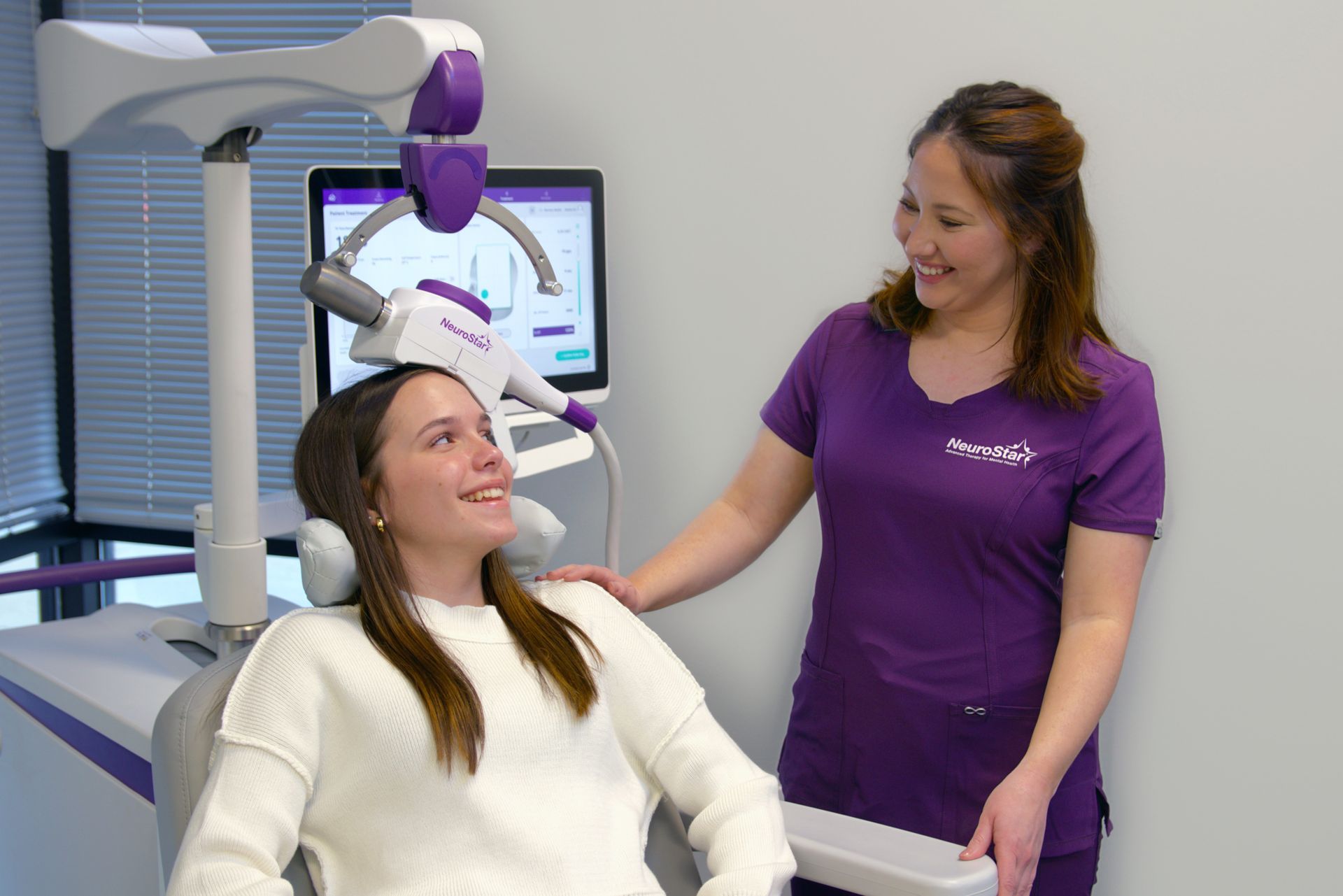 A woman is sitting in a dental chair with a nurse standing next to her.