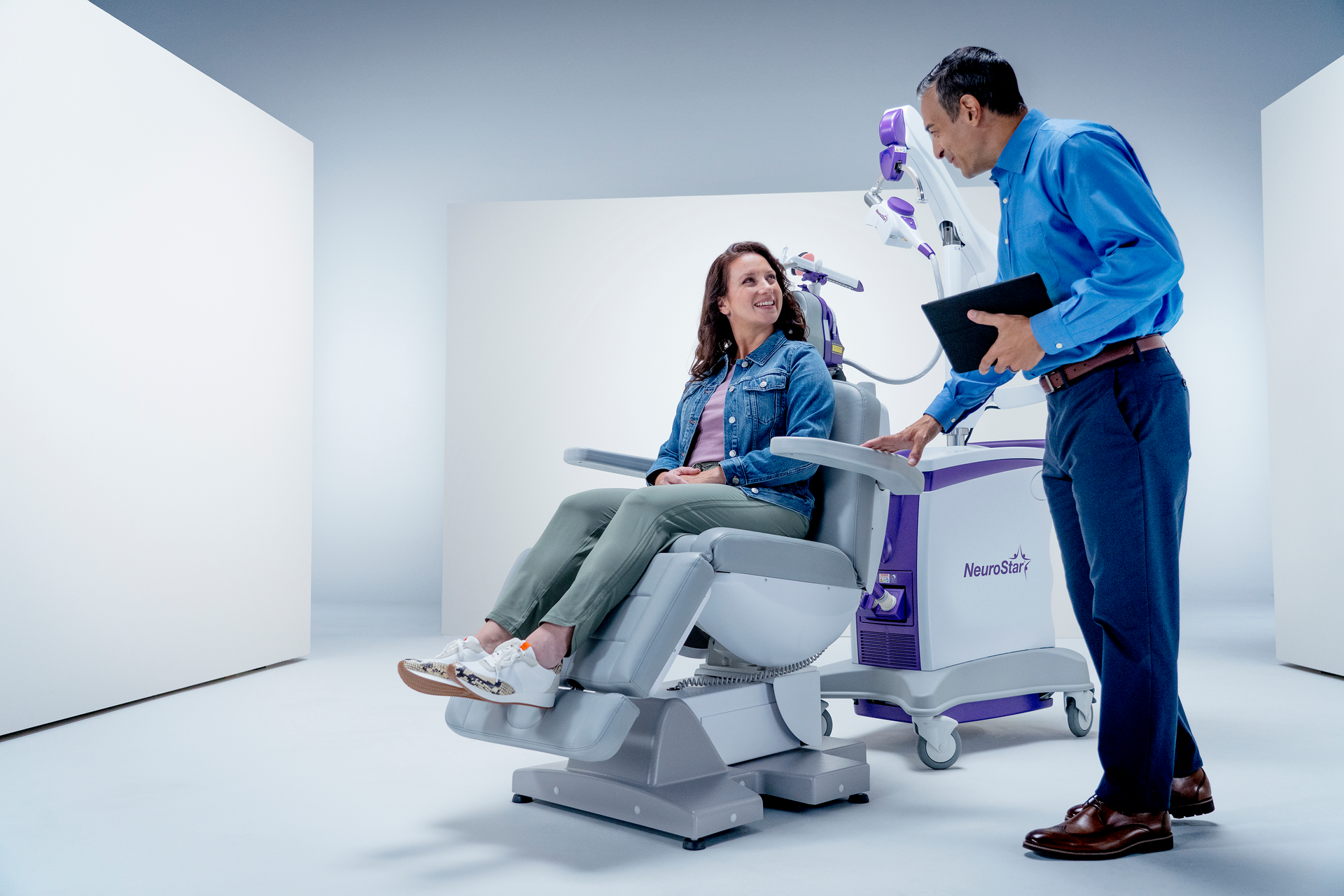 A man is standing next to a woman sitting in a chair.