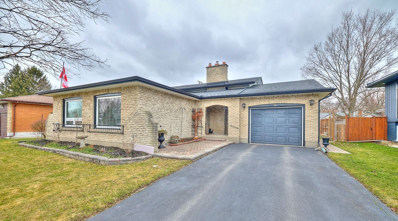 A picture of a detached back split home with brick and a Canadian flag on a flag pole.