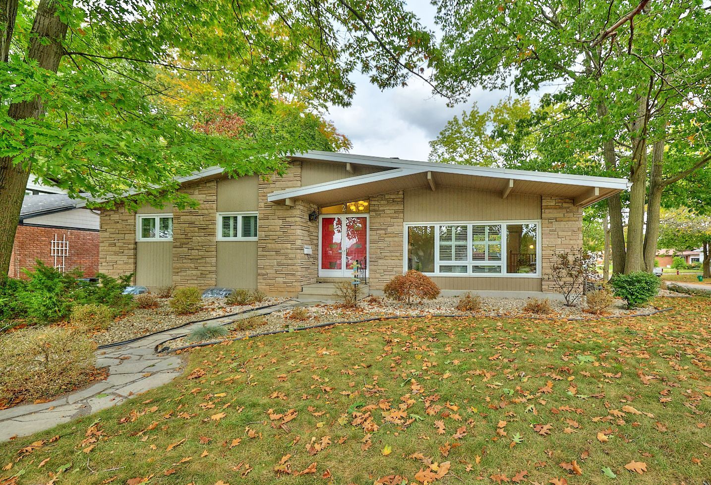 A detached bungalow surrounded by fall trees.