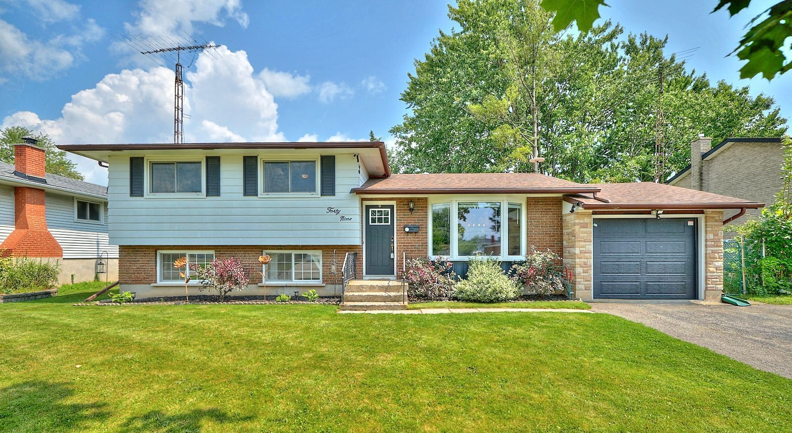 A picture of a sidesplit residential home with white siding and brick.