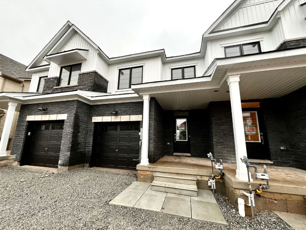 A picture of a black and white vinyl siding/brick townhouse in a new development in Welland, Ontario.