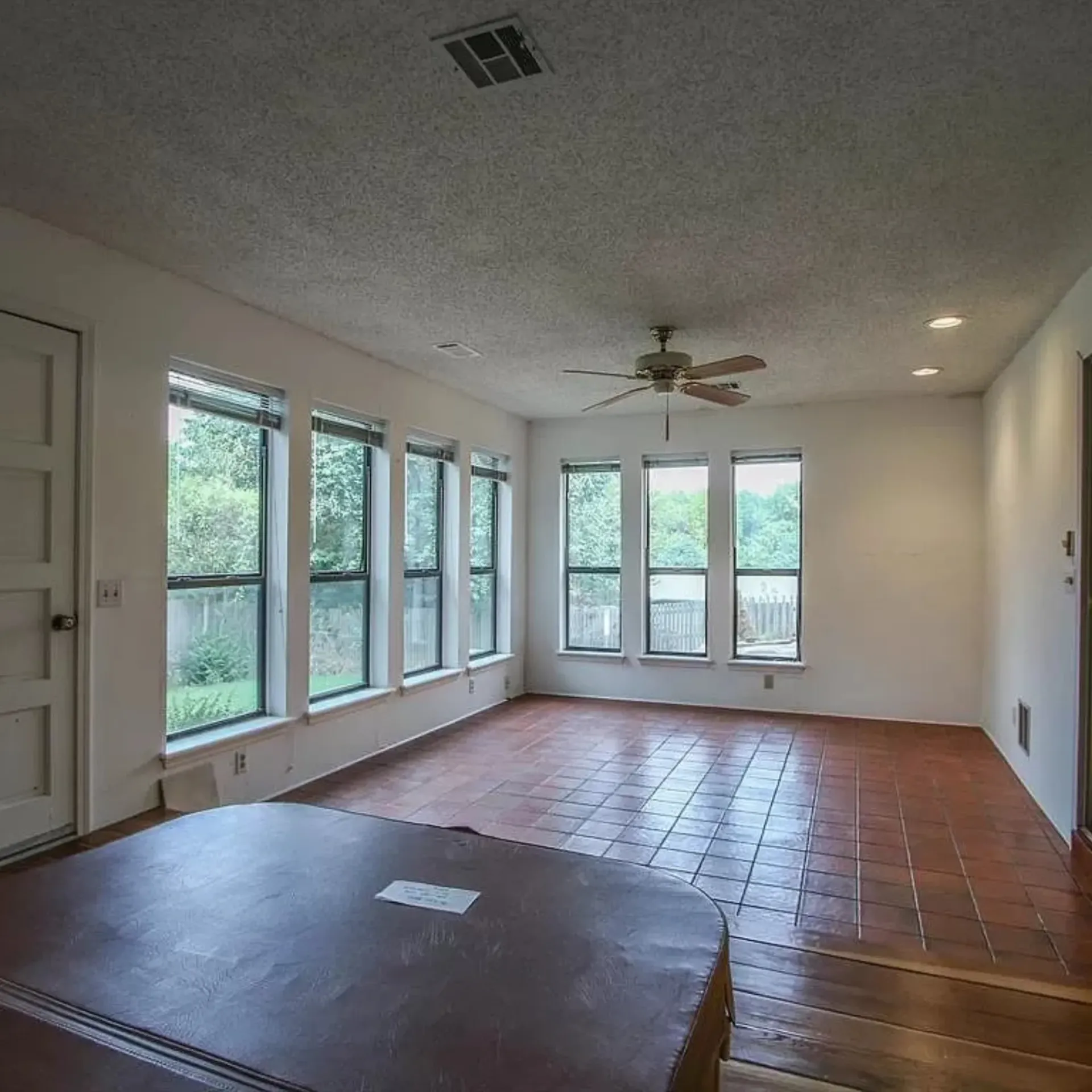 Aarons Repair and Remodel - An empty living room with a ceiling fan and lots of windows