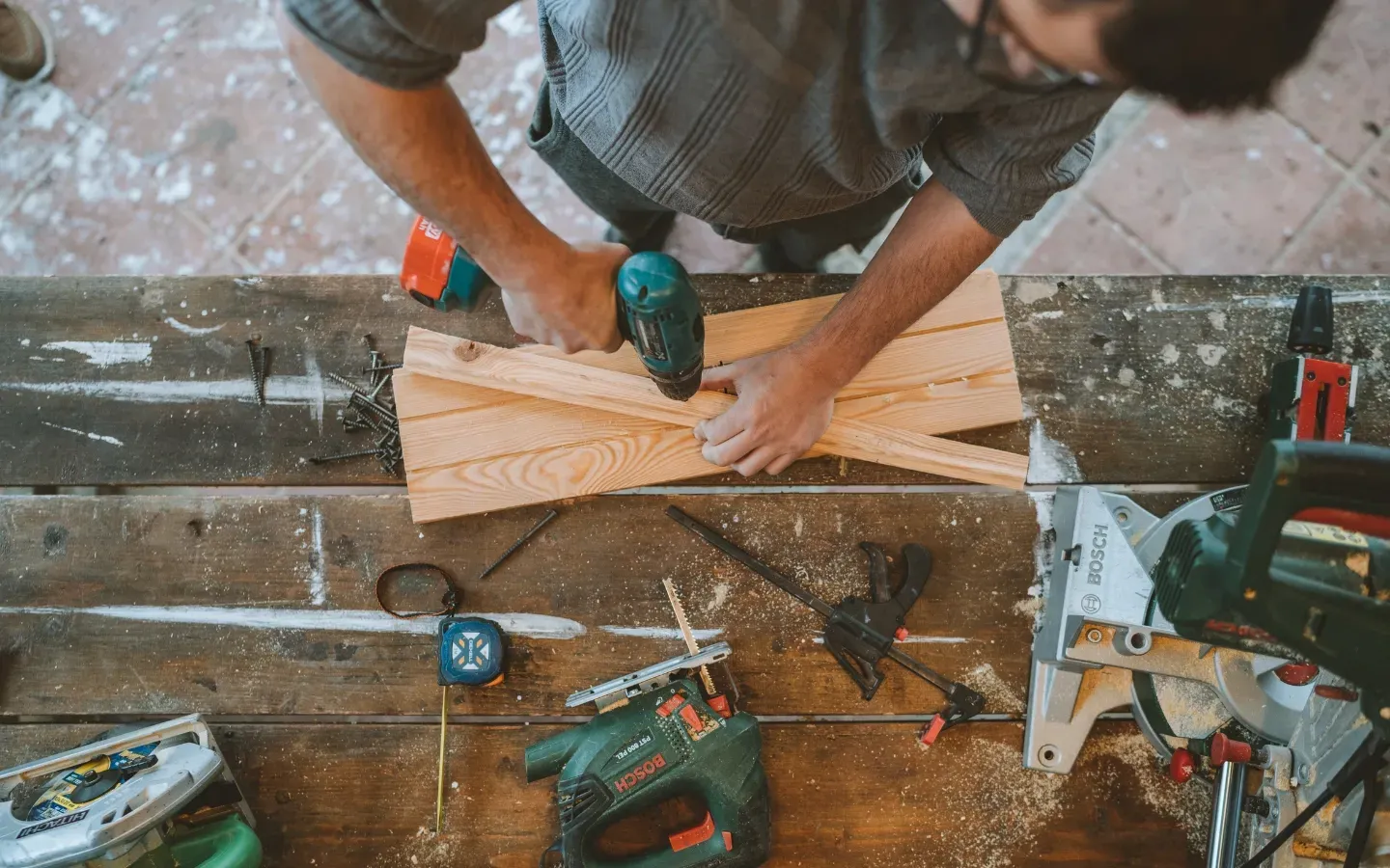 A man is working on a piece of wood on a wooden table.