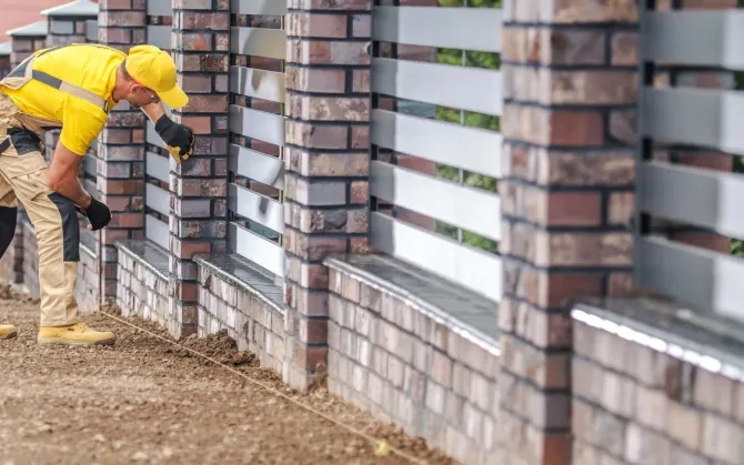 Aarons Repair and Remodel - A man is working on a brick fence.