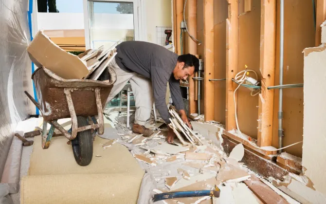 Aarons Repair and Remodel - A man is working on a house with a wheelbarrow.