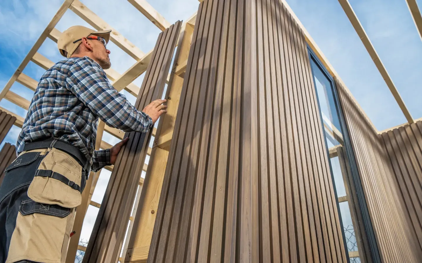 A man is measuring a wooden wall with a tape measure.